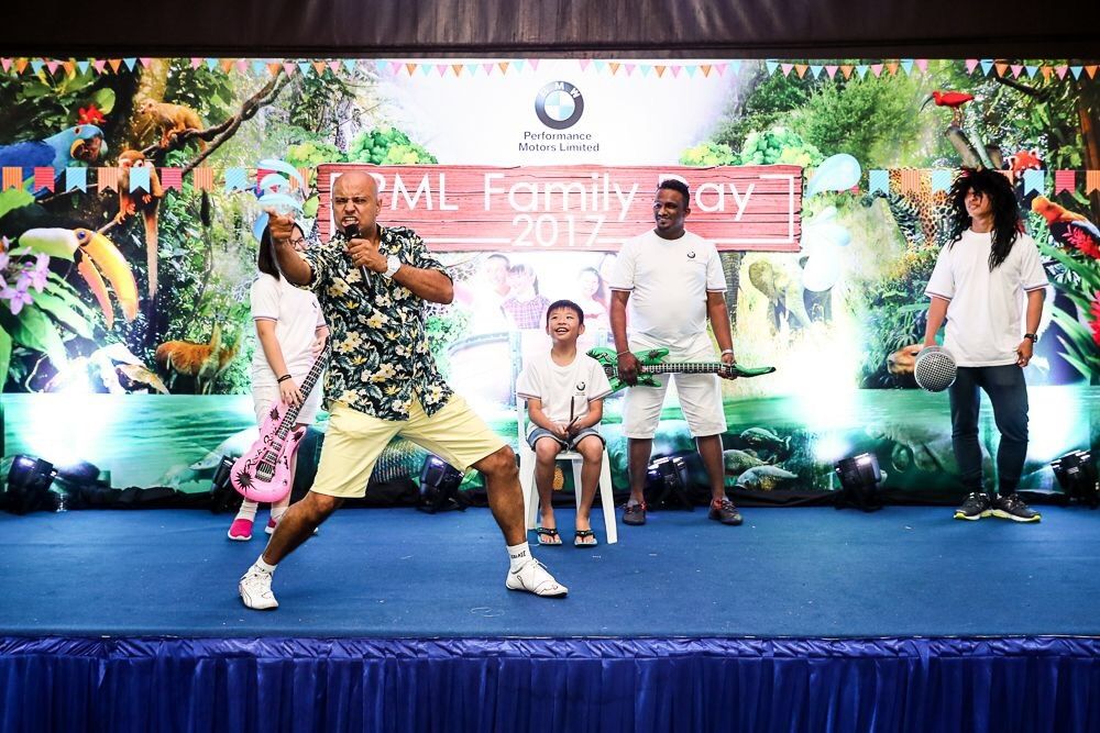 Rico Smith striking an air guitar pose with kids on stage at the PML Family Day