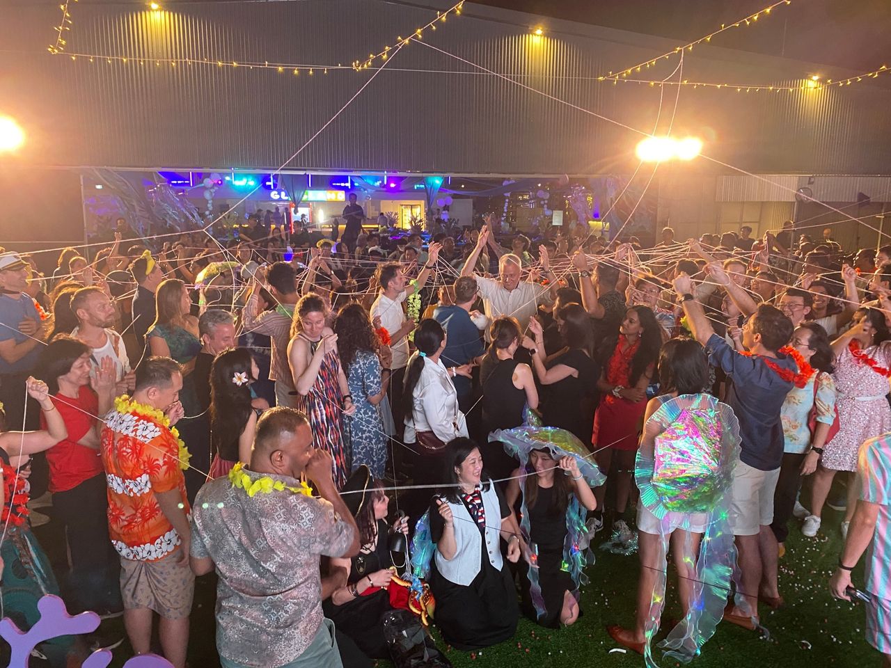 Party guests tangled up in a string web game at a beach-themed event