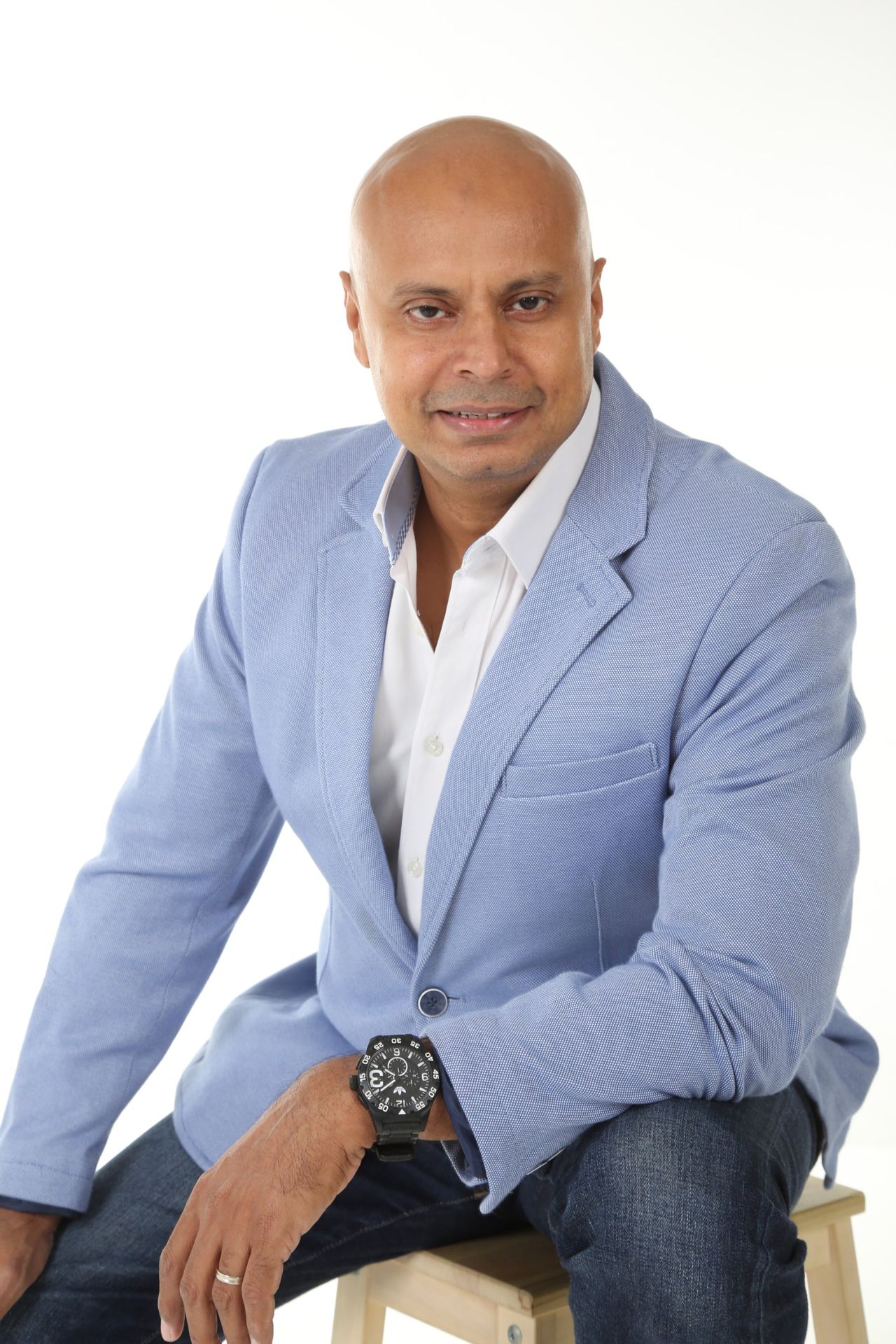 Rico Smith in a light blue blazer, seated on a stool